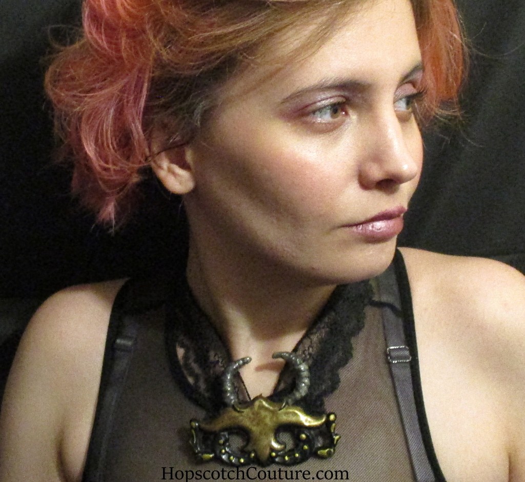 Close up of handmade demon pendant necklace made from antique hardware and vintage black lace. This was handmade by Marelle Couture for Hopscotch Couture. https://hopscotchcouture.com/products/masked-demon-pendant-statement-brass-necklace-unique-horned-brass-devil-pendant-dark-n-delightful-jewelry-ooak?_pos=1&_psq=demon&_ss=e&_v=1.0 #demonnecklace #devilpendant #gothnecklace 