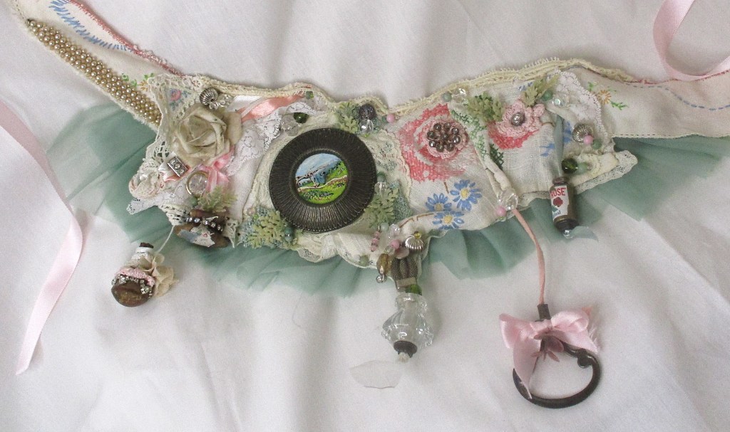 Handmade bridal sash or bib necklace. 2 in 1 bridal accessory by Marelle Couture for Hopscotch Couture. Made with all antique hardware and vintage materials. https://hopscotchcouture.com/products/large-trinket-bib-necklace-fairytale-princess-sash-neck-piece-antique-assemblage-statement-bib-bridal-necklace #bridalaccessory #bridalbibnecklace #bridalsash